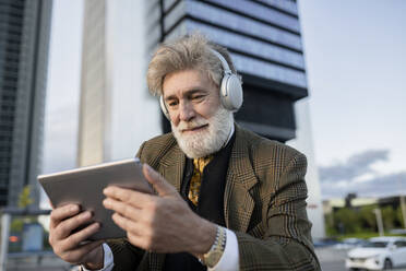 Businessman watching video on digital tablet in city - JCCMF02628