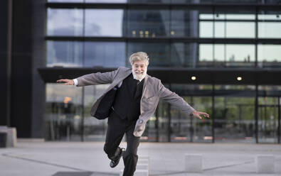 Cheerful businessman in front of office building - JCCMF02636