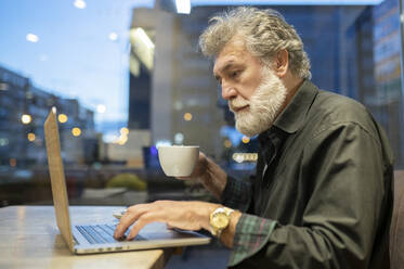 Geschäftsmann mit Laptop bei der Arbeit in einem Café - JCCMF02652