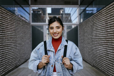 Young woman smiling while standing in front of building - TCEF01866