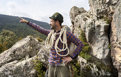 Männlicher Tourist mit Seil und Rucksack, der auf einem Berg steht - VEGF04564