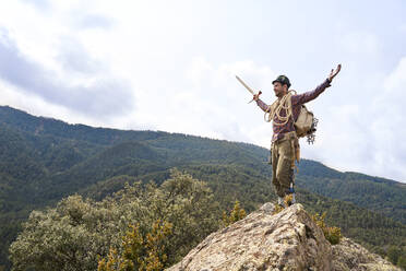 Carefree male tourist standing with arms outstretched on mountain - VEGF04567