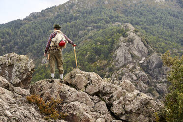 Mittlerer erwachsener männlicher Bergsteiger, der auf einem Berg stehend die Aussicht betrachtet - VEGF04569