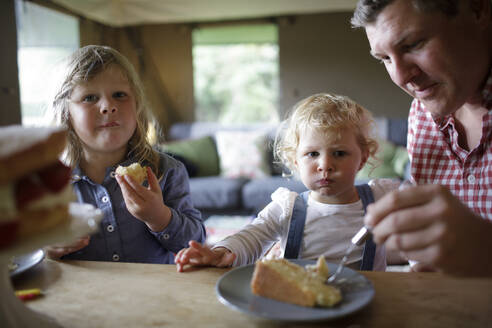 Vater und Töchter essen Kuchen am Esstisch - CAIF30358