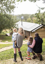 Eltern und Töchter betrachten die Hütte vom Waldweg aus - CAIF30360