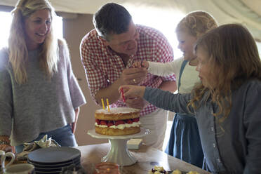 Family celebrating birthday with strawberry cake and candles - CAIF30363