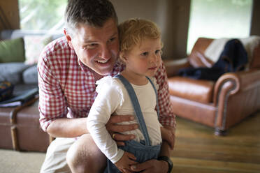 Father hugging daughter in living room - CAIF30365