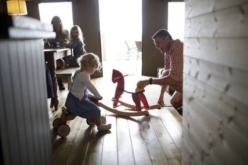 Family plying with rocking horse and toys in cabin - CAIF30370