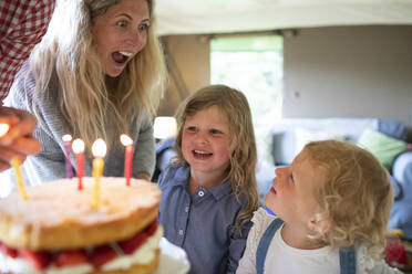 Glückliche Mutter und Töchter feiern Geburtstag mit Kuchen und Kerzen - CAIF30372