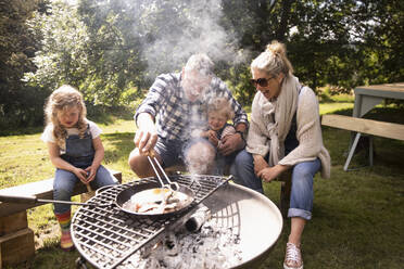 Glückliche Familie beim Frühstück auf dem Camping-Grill - CAIF30386