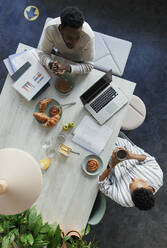 Business people talking over breakfast at office table - CAIF30410