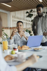 Business people planning at breakfast meeting in office - CAIF30434