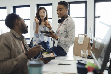 Geschäftsleute essen Mittagessen zum Mitnehmen am Schreibtisch in einer Bürobesprechung - CAIF30449