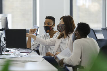 Business people in face masks working at computer in office - CAIF30451
