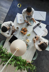 Business people talking over breakfast in office meeting - CAIF30478