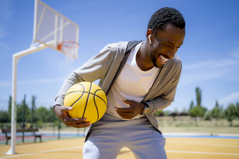 Mann hält Basketball, während er auf dem Sportplatz steht - OCMF02117