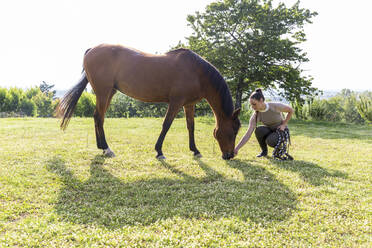 Frau füttert Pferd in der Hocke auf einer Ranch - WPEF04586