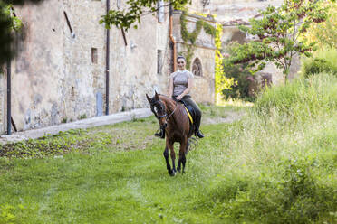 Woman riding on horse at grass area - WPEF04597