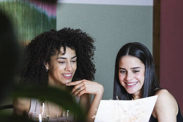 Lächelnde Freunde lesen Speisekarte im Restaurant - PNAF01716