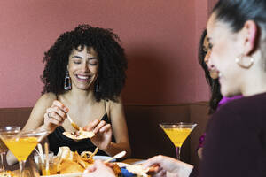 Lächelnde Frau beim Aperitif mit Freunden im Restaurant - PNAF01727