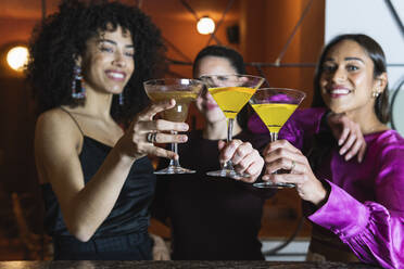 Weibliche Freunde stoßen in einem Restaurant mit einem Martini-Glas an - PNAF01734