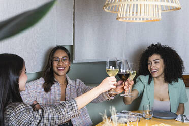 Unternehmerinnen stoßen im Restaurant mit Weingläsern an - PNAF01750