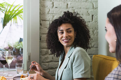 Lächelnde Geschäftsfrau, die einen Kollegen im Restaurant ansieht - PNAF01752