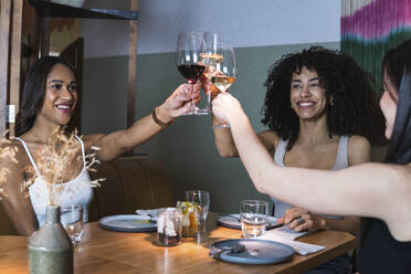 Glückliche Frauen stoßen mit Weingläsern während einer Party im Restaurant an - PNAF01761