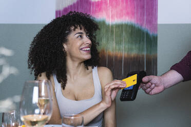 Smiling woman paying through credit card at restaurant - PNAF01762