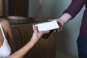 Young woman paying through smart phone at restaurant - PNAF01763