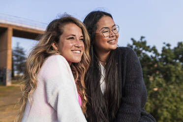 Smiling female friends looking away in park - JRVF00888