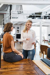 Junge weibliche Fachkräfte diskutieren über ein Dokument in einem kreativen Büro - DIGF15378