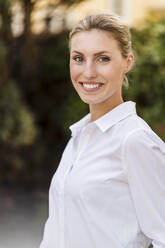 Lächelnde schöne Geschäftsfrau mit blondem Haar im Freien - DIGF15409