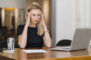 Müde weibliche Fachkraft sitzt am Schreibtisch im Büro - DIGF15445