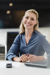 Schöne glückliche weibliche professionelle sitzen am Schreibtisch im Büro - DIGF15456