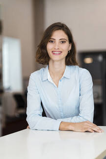 Young cheerful brunette business lady posing at camera smiling, in formal  clothes, leaned on office desk, looking at camera happily, enjoying office  w Stock Photo - Alamy