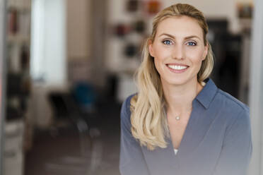 Schöne lächelnde Geschäftsfrau mit blondem Haar im Büro - DIGF15467