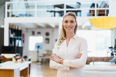 Beautiful smiling female professional standing with arms crossed in creative office - DIGF15472