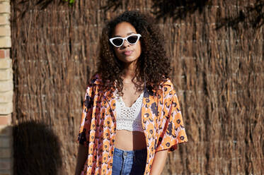 Young woman with sunglasses in front of straw wall - KIJF03864