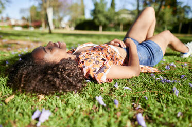 Junge Frau entspannt sich im Liegen im Park - KIJF03879