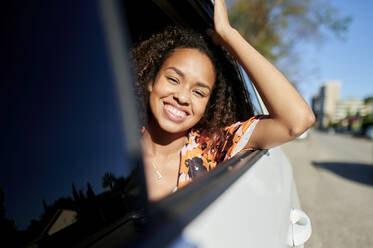 Lächelnde Frau, die an einem sonnigen Tag im Auto unterwegs ist - KIJF03887