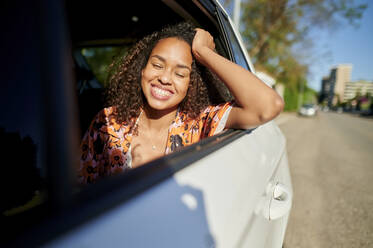 Woman with hand in hair traveling on sunny day - KIJF03888