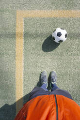 Mann steht vor einem Fußball auf einem Feld - MMFF01313