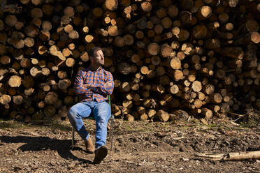 Holzfäller mit verschränkten Armen auf einem Stuhl sitzend in der Holzindustrie - VEGF04589