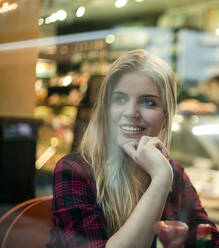 Blonde Frau schaut weg, während sie im Café sitzt - AJOF01372