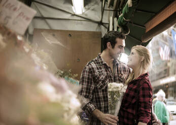 Boyfriend giving flowers to girlfriend at store - AJOF01375