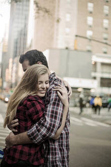Affectionate young couple embracing on street in city - AJOF01377