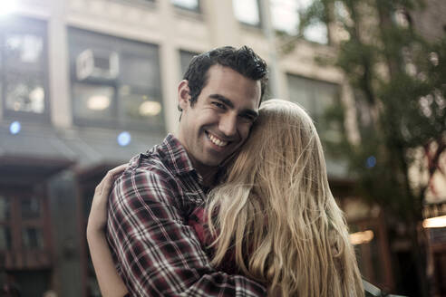 Smiling boyfriend embracing girlfriend in city - AJOF01378