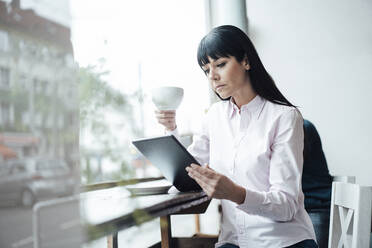 Geschäftsfrau, die ein digitales Tablet benutzt, während sie in einem Café sitzt - JOSEF04572