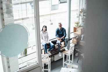 Weibliche und männliche Unternehmer sitzen am Fenster eines Cafés - JOSEF04583